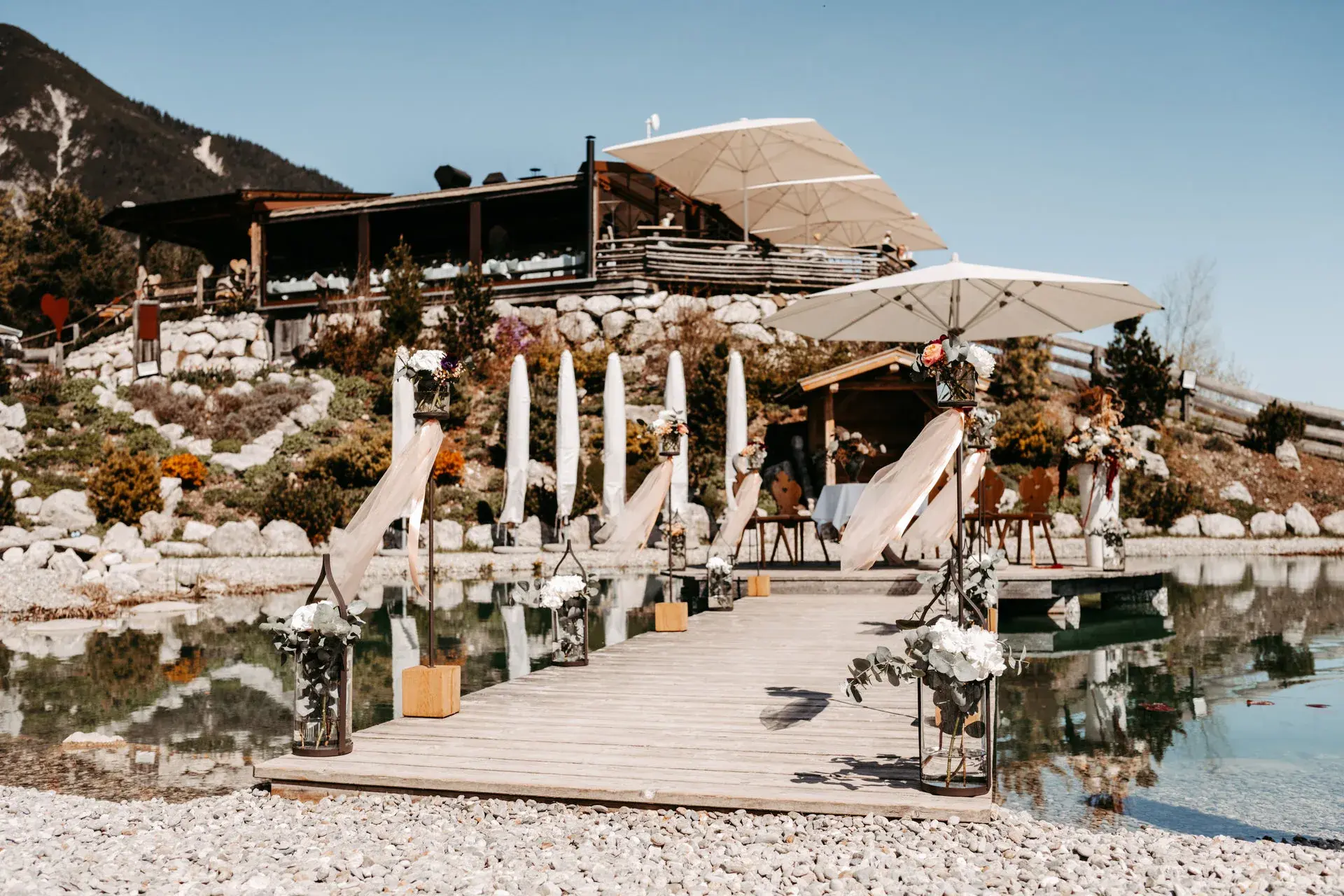 Decorated wooden jetty across the Stöttlalmsee to the ceremony spot, the Stöttlalm hut and Mieming mountains above in Tyrol