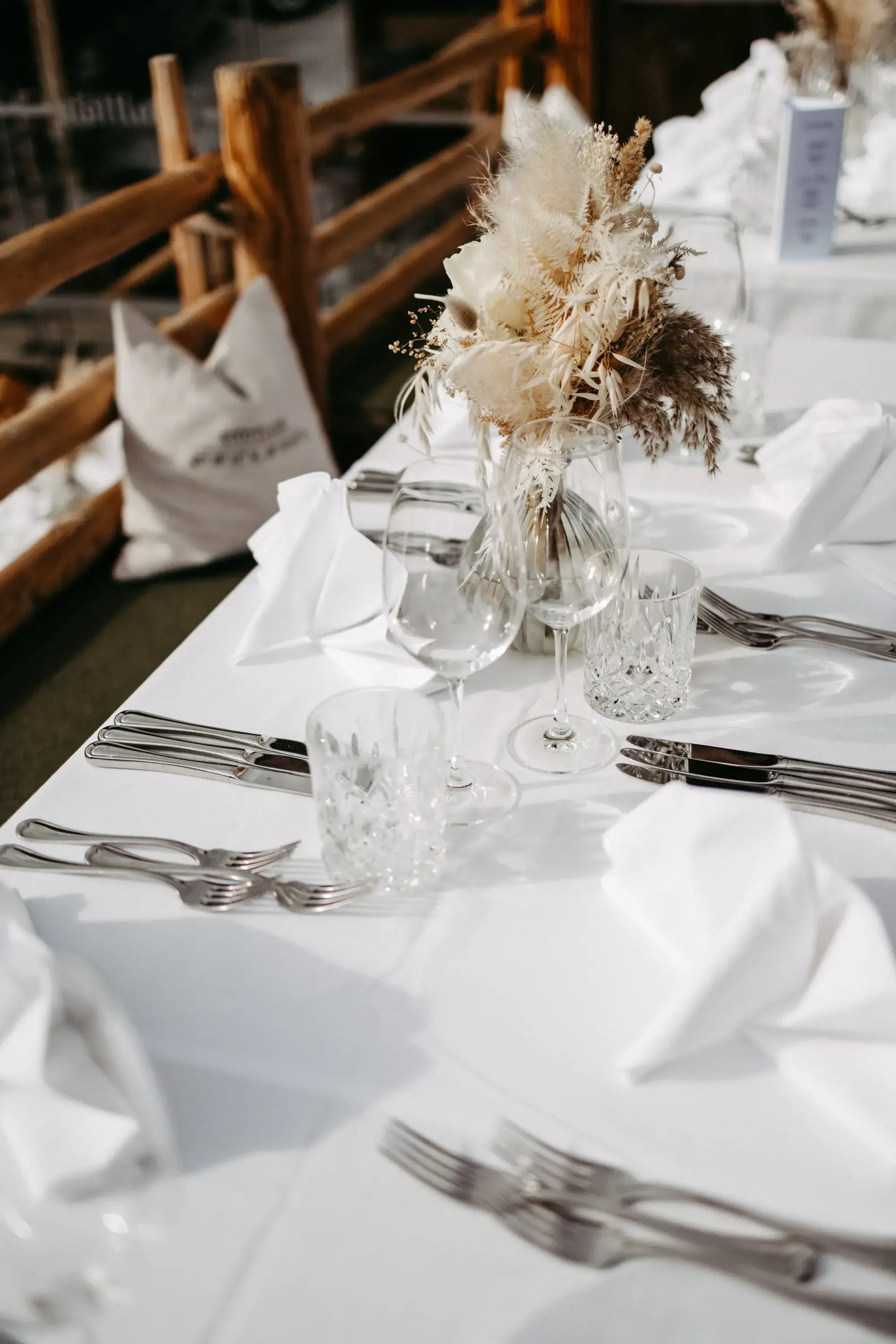 Festively laid table with pampas grass and dried flowers in front of the rustic wooden wall of the Stöttlalm in Tyrol