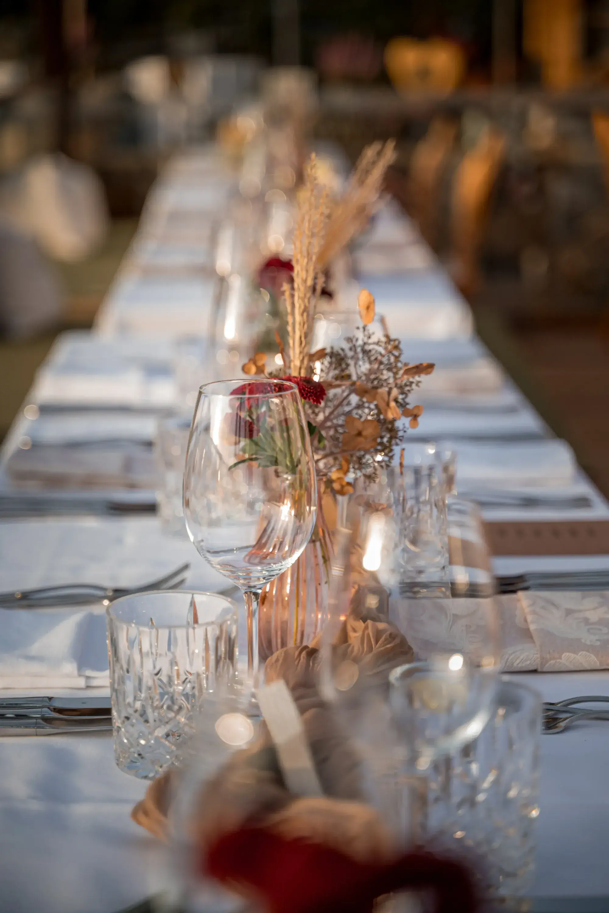 Long banquet table with crystal glasses, dried flowers and candlelight in an evening atmosphere at the Stöttlalm
