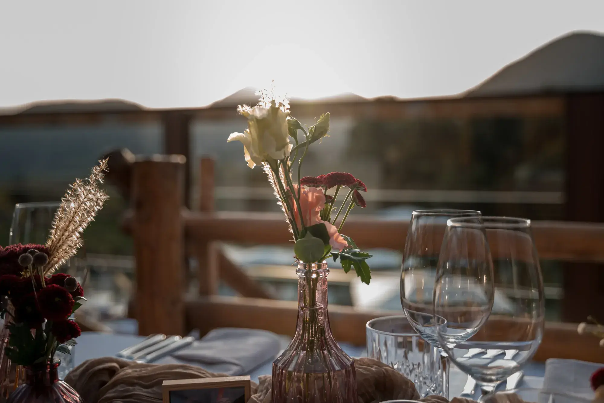 Floral decoration in a pink vase on a laid terrace table at the Stöttlalm, backlit by the warm glow of sunset