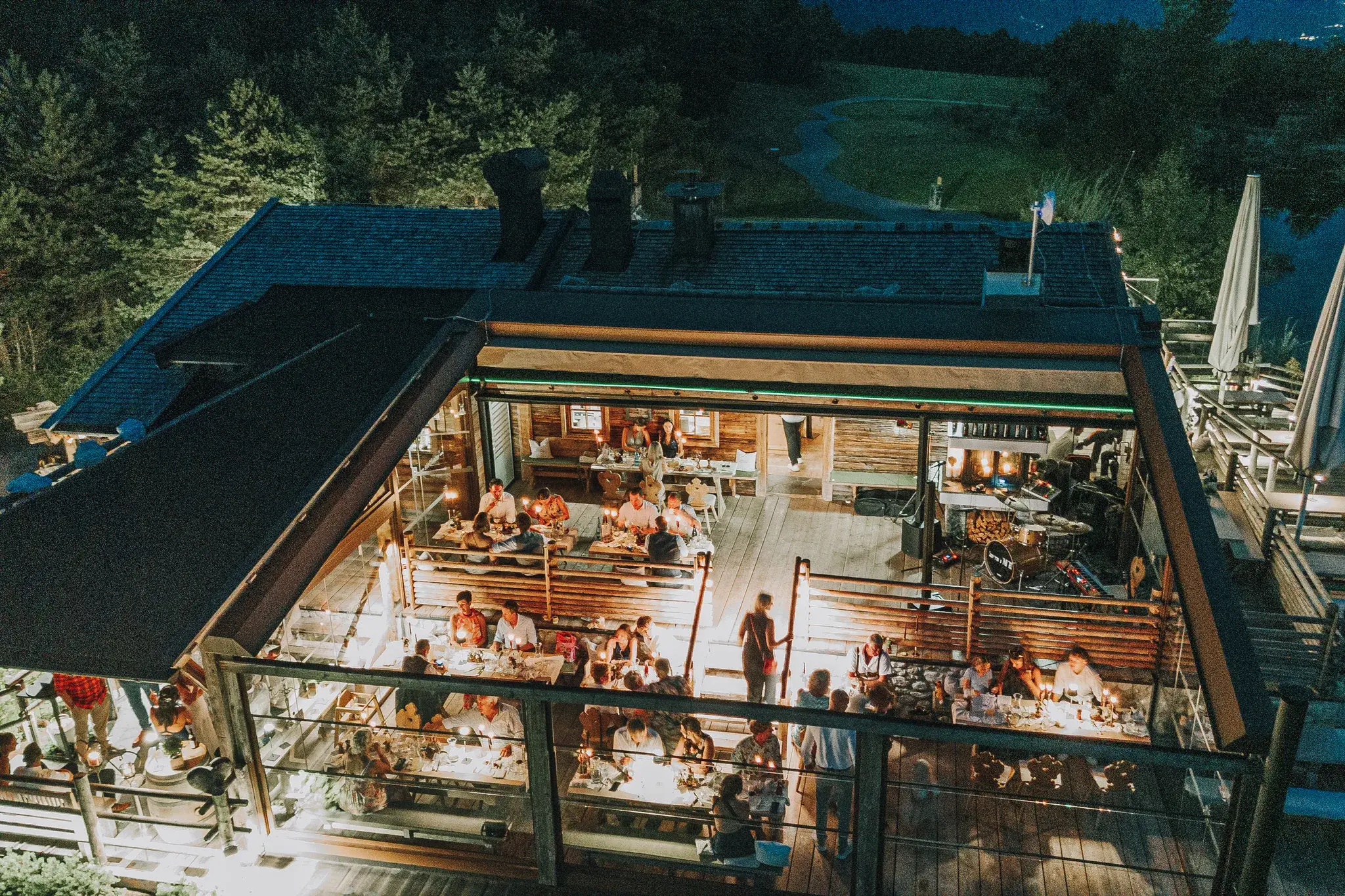 Aerial view of an evening wedding reception on the brightly lit Stöttlalm terrace at dusk in Tyrol