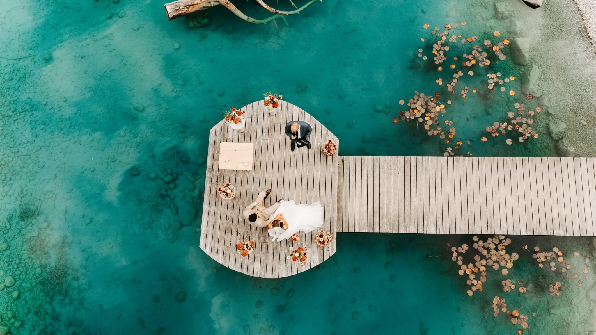 Aerial view of a bride and groom having a picnic on the jetty above the turquoise Stöttlalmsee in Tyrol