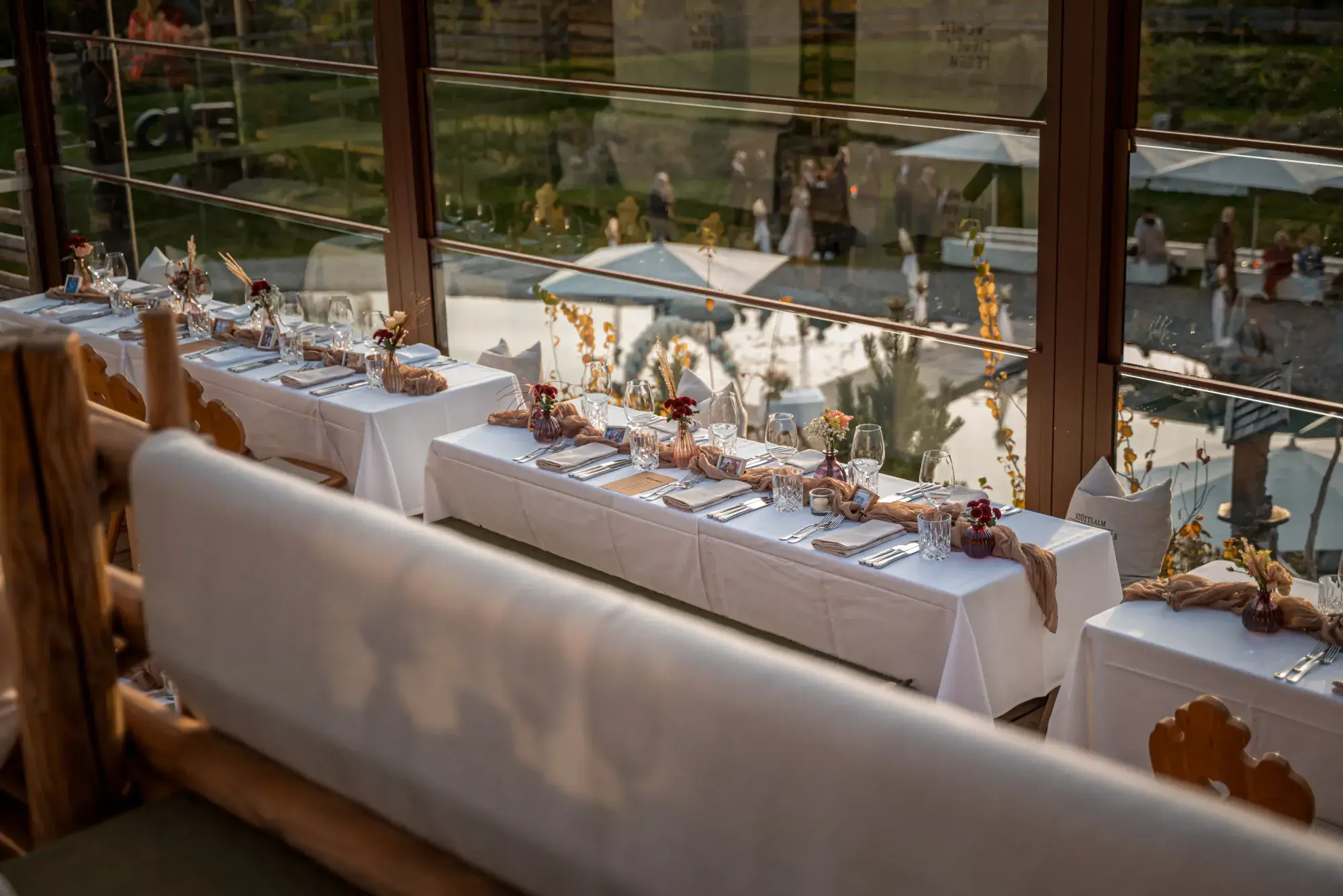 Banquet tables with autumn decoration along the panorama windows of the Stöttlalm, an exclusive event venue in Tyrol