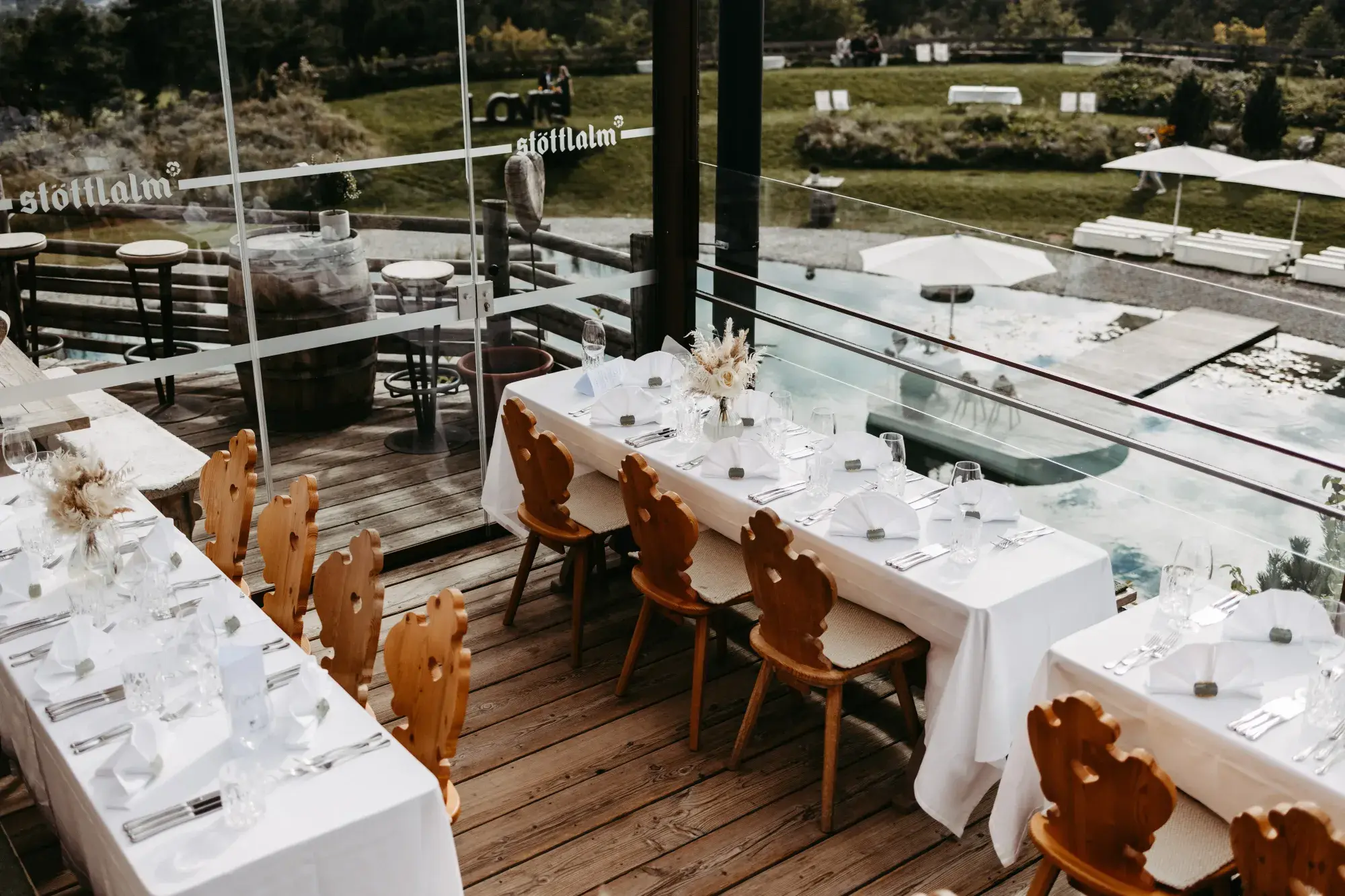 Festively laid tables with Tyrolean wooden chairs on the terrace overlooking the Stöttlalmsee, set for a confirmation celebration