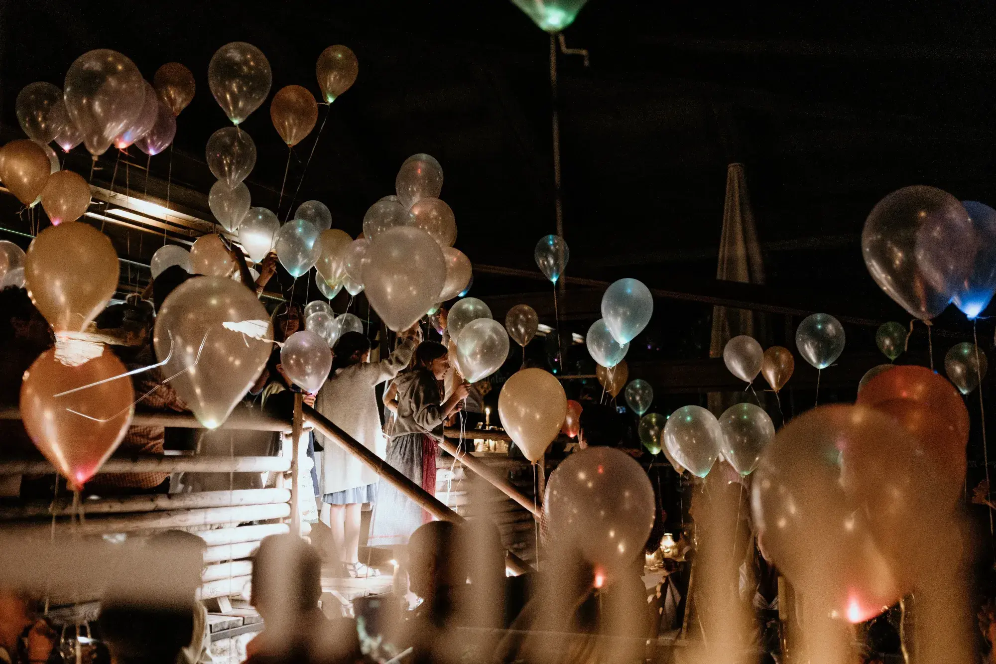 Glowing balloons rising into the night sky during an evening birthday party on the Stöttlalm terrace in Tyrol