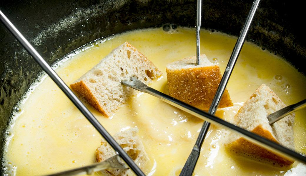 Bread cubes on fondue forks dipped into a pot of melted cheese fondue, a Tyrolean speciality at the Stöttlalm