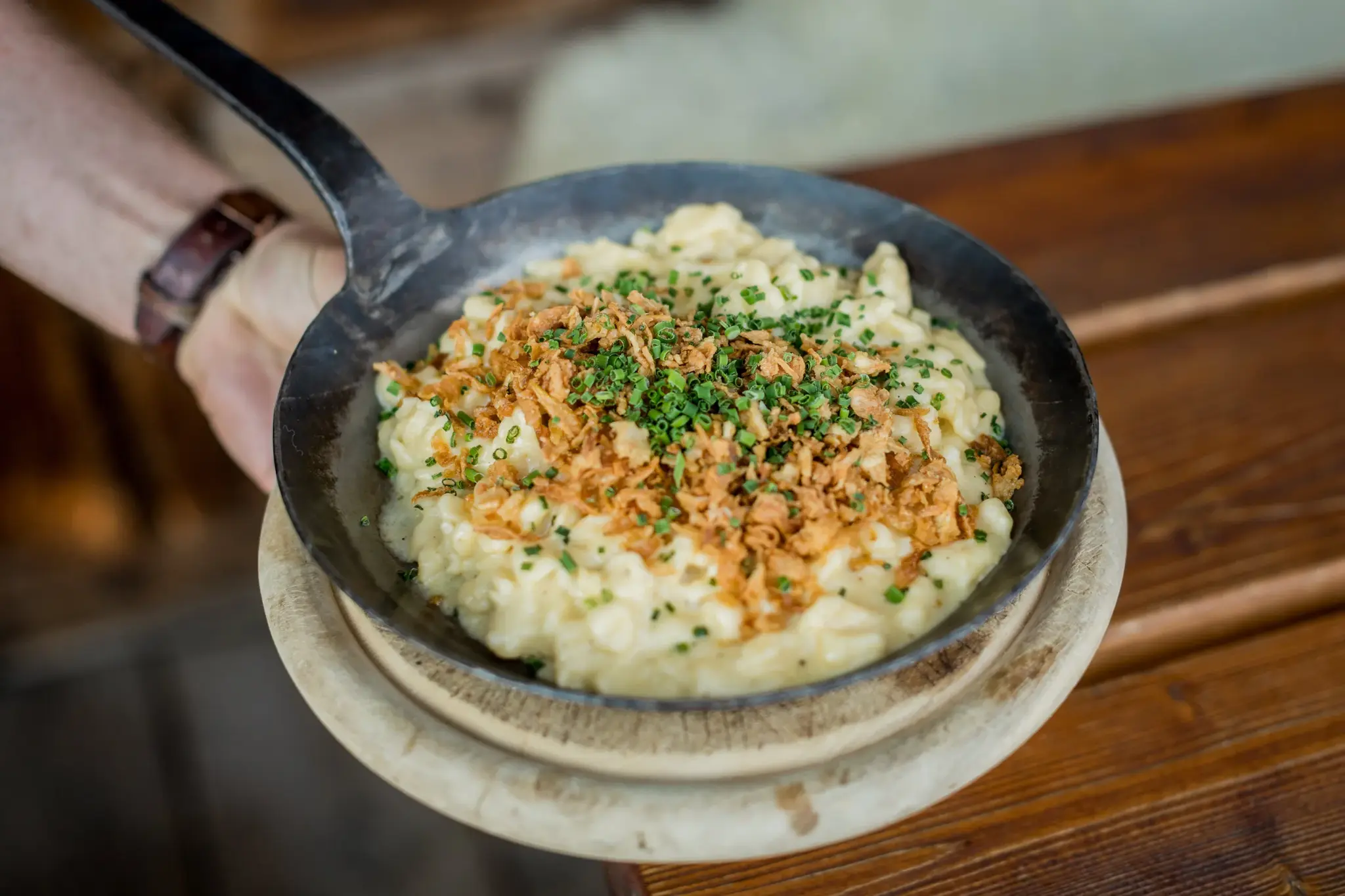 Steaming cheese spaetzle with fried onions and chives in a pan, a Tyrolean speciality at the Stöttlalm