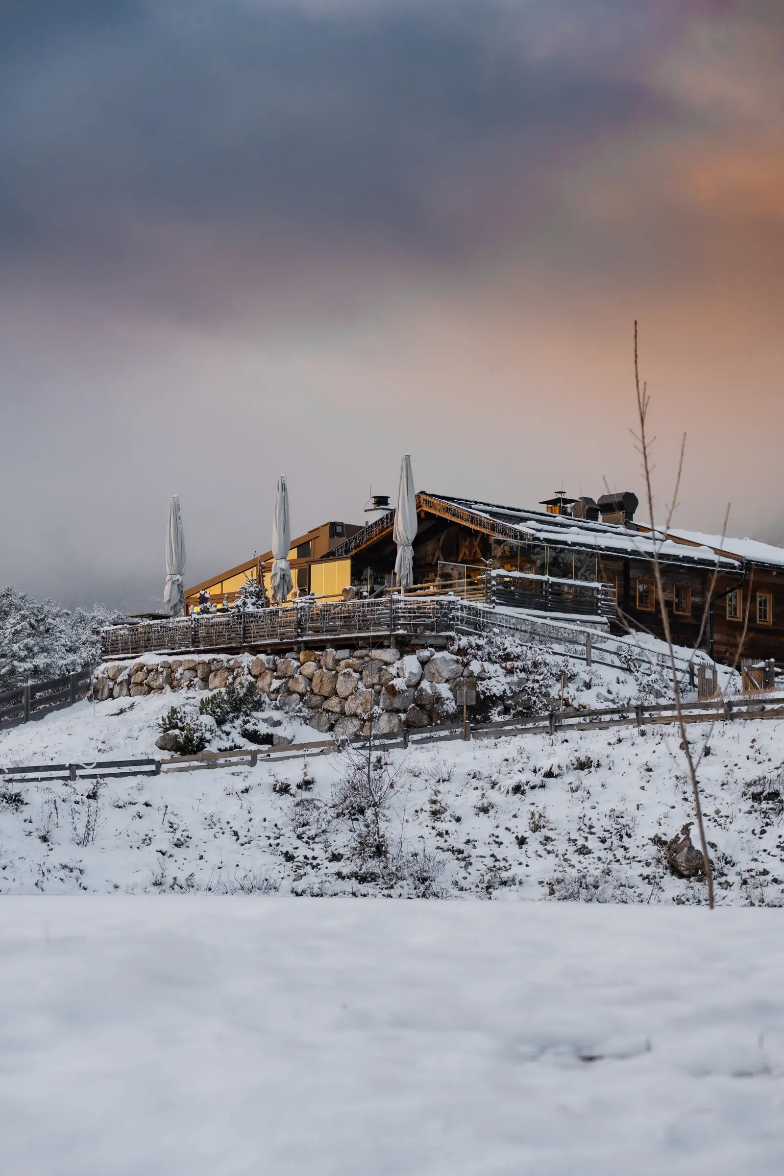 Snow-covered Stöttlalm alpine hut and sun terrace before the Mieminger Kette at pink winter twilight, ideal for Christmas parties